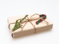 A present or gift box wrapped by rough brown recycled paper and tied with brown hemp rope ribbon with pine branch and candy cane i Royalty Free Stock Photo