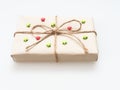 A present or gift box wrapped by rough brown recycled paper and tied with brown hemp rope as ribbon with red and green star isola Royalty Free Stock Photo