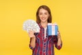 Present and money bonuses. Portrait of beautiful happy ginger girl in casual checkered shirt standing holding gift box and dollars Royalty Free Stock Photo