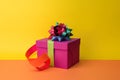 Present in purple gift box with green and red ribbons and colorful bow on top. Happy Birthday concept. Royalty Free Stock Photo