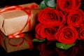 Present with red ribbon and bouquet of beautiful red roses. Mothers Day