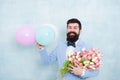 Present for spouse. Guy with air balloons. Birthday party. Bearded man hipster with flower bouquet. Womens day. Bearded