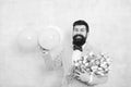 Present for spouse. Guy with air balloons. Birthday party. Bearded man hipster with flower bouquet. Womens day. Bearded