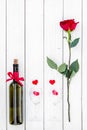 Present for Valentine day in red colors. Wine, glasses, red rose, heart sign, gift box on white wooden background top