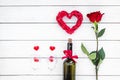 Present for Valentine day in red colors. Wine, glasses, red rose, heart sign, gift box on white wooden background top