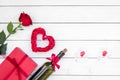 Present for Valentine day in red colors. Wine, rose, heart sign, gift box on white wooden background top view copy space