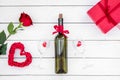 Present for Valentine day in red colors. Wine, rose, heart sign, gift box on white wooden background top view copy space