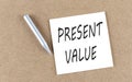 PRESENT VALUE text on a sticky note on cork board with pencil Royalty Free Stock Photo
