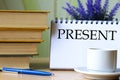 PRESENT - word in a notebook on a background of old books with pen and white cup Royalty Free Stock Photo