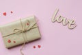 Present wrapped in brown craft paper and tie hemp string on Light pink background. Romantic Gift with decorative red Royalty Free Stock Photo