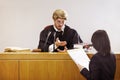 Present your case.... Serious young judge sitting in the courtroom with a stern facial expression. Royalty Free Stock Photo