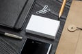 Blank business cards on a black table top with office supplies