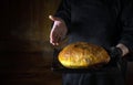 Presentation of freshly baked wheat bread in the hands of a baker. Space for advertising. The concept of baking bread at home