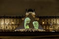 A presentation of Louvre collection displayed on a glass pyramid entrance in the evening, Paris