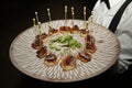 Presentation of small slices of bread with a mackerel skewer with caviar during a catering event. Food concept, menu, catering