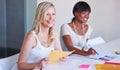 Presenting their creative ideas. A young businesswoman smiling while sitting at her desk with a colleague. Royalty Free Stock Photo