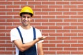 Presenting young worker in front of a brick wall Royalty Free Stock Photo