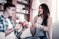 Openly laughing woman presenting her gift to boyfriend nearby