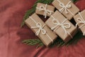 Presents for a Christmas. Gift boxes wrapped in craft paper and tie white string. Red velvet cloth background. Holiday mood. Royalty Free Stock Photo