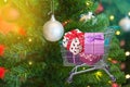 Presents ribbon gift box in shopping trolley cart with christmas tree and balls decorations and blurred lights