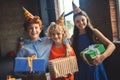 Three friends in bday hats holding presents Royalty Free Stock Photo