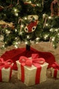 Presents under Bright Decorated Christmas Tree Red Ribbon Wrapped Gifts
