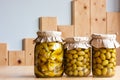 Preserved fermented olives and artichokes in olive oil in glass jars cut on wooden background. Autumn vegetables canning Royalty Free Stock Photo