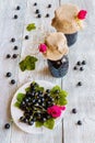 Preserved homemade black currant jam in glass jars on wooden table. Fresh berries and green leaves, vintage white plate, top view Royalty Free Stock Photo