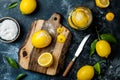 Preserved, salted canned lemons on a wooden board over black stone background. Moroccan cuisine.