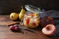 Preserving peach, pear and plums with cinnamon and cloves in a glass jar on rustic wood to have canned fruits in winter, vintage Royalty Free Stock Photo