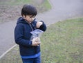 Preshool kid preparing seeds. for feeding the duck, Happy boy holding plastic bag with animal food in the park. Child explorer and