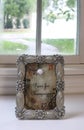 Press for Champagne sign with button to push in ornate silver frame sits in front of wood framed window with screen on rainy summe
