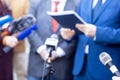 News conference, journalists with microphones interviewing politician or business person during media event