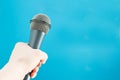Press microphone, journalist`s hand holding speaker, isolate on blue Royalty Free Stock Photo
