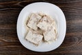 Pressed pieces of pollock fillet in flour on dish on wooden table. Top view