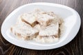 Pressed pieces of pollock fillet in flour on white dish on table