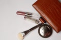 Pressed powder, brush and lipsticks dropping out from a female purse Royalty Free Stock Photo