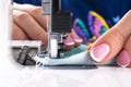 Presser foot of sewing machine with needle and thread close up. Detail of sewing machine with female fingers. Women`s hands sewin