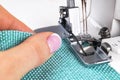 Presser foot of sewing machine with needle and thread close up. Detail of sewing machine with female fingers. Women`s hands sewin