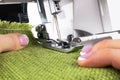 Presser foot of sewing machine with needle and thread close up. Detail of sewing machine with female fingers. Women`s hands sewin