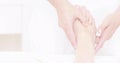 Pressing practitioner hands and forearms massaging bare foot on table in spa, with white uniform Royalty Free Stock Photo