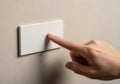 Is pressing a white rectangular light switch mounted on a beige Royalty Free Stock Photo
