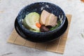 Pressure cooker pork belly Kakuni with cabbage, Japanese scallion, shiitake, carrot served in blue ceramic bowl on makisu.