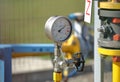 Pressure gauge for measuring the pressure of natural gas in a gas pipeline. Yellow transport pipes on the surface of the fence.