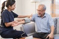 Pressure measurement of hypertension in elderly man sitting on couch, young woman nurse or caregiver care checking, measuring Royalty Free Stock Photo