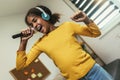 Preteen black girl holding microphon singing karaoke at home, recording songs for contest. Children's lifestyle concept