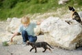 Preteen boy enthusiastically plays with cute kittens. Little boy strokes funny wildcats on the street of a small seaside town. Royalty Free Stock Photo