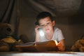 Preteen boy with flashlight reading book at home Royalty Free Stock Photo