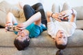 Preteen boy and girl using smartphones for on-line conversation, kids lying back on sofa, idleness Royalty Free Stock Photo