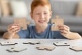 Preteen boy holding two pieces of wooden puzzles